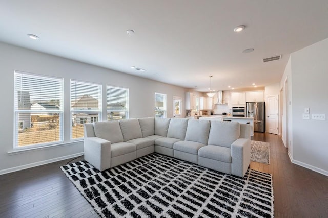 living room with dark wood-style flooring, recessed lighting, visible vents, and baseboards