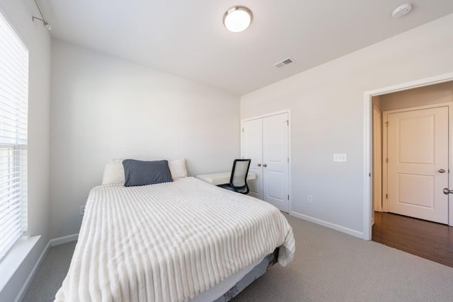 carpeted bedroom with a closet, visible vents, baseboards, and multiple windows