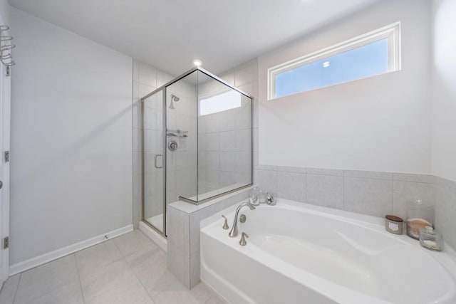 bathroom featuring a stall shower, tile patterned flooring, a garden tub, and baseboards