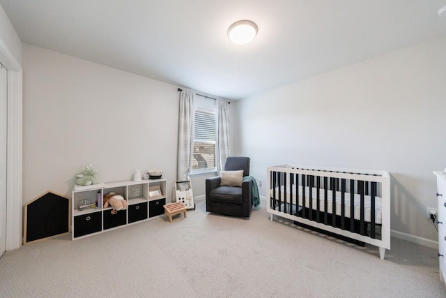 bedroom featuring a crib, carpet, and baseboards