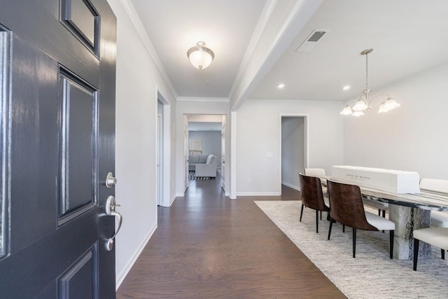 foyer entrance featuring a notable chandelier, dark wood-style flooring, visible vents, baseboards, and ornamental molding