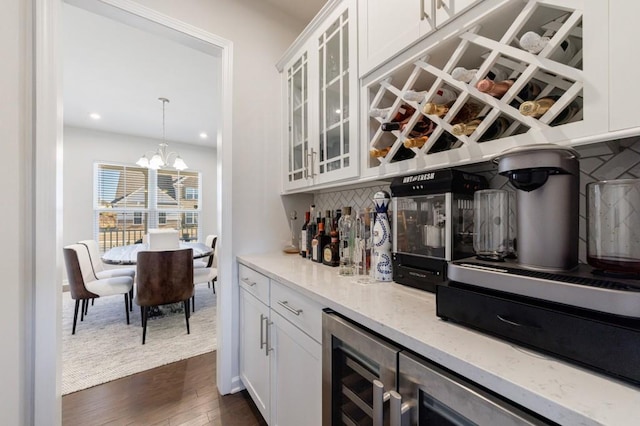 bar featuring wine cooler, a notable chandelier, decorative backsplash, a bar, and dark wood finished floors