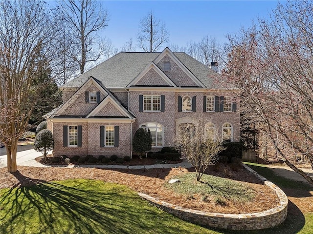 colonial house with a front yard, brick siding, and a chimney