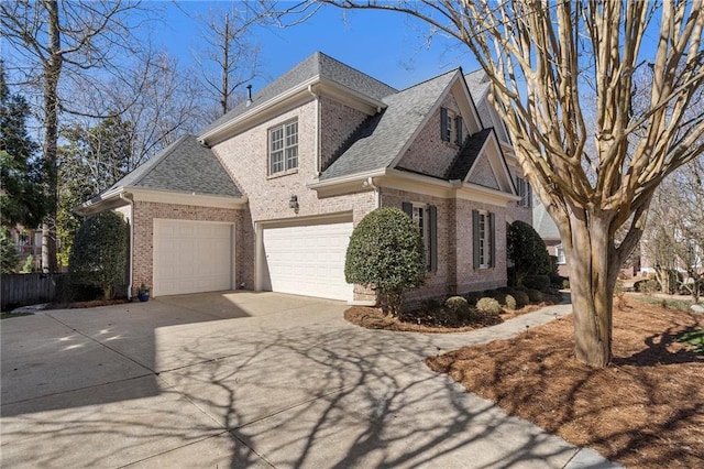 view of front of house featuring a shingled roof, brick siding, driveway, and a garage