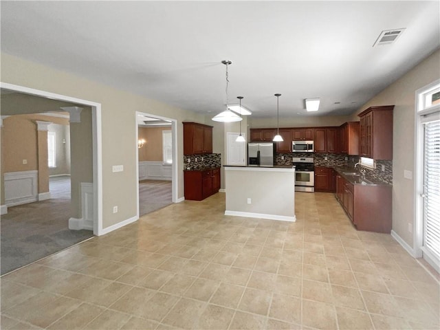 kitchen with stainless steel appliances, sink, decorative light fixtures, tasteful backsplash, and a kitchen island