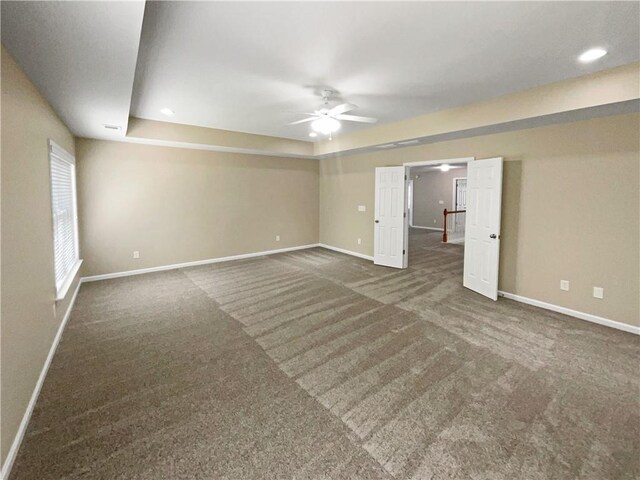 empty room with ceiling fan and dark carpet