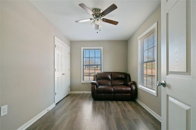 living area featuring dark wood-type flooring and ceiling fan