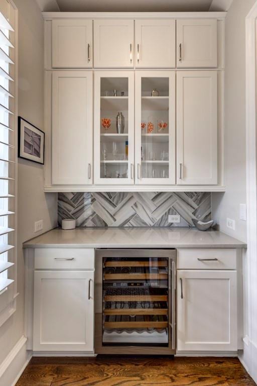 indoor dry bar featuring wine cooler, decorative backsplash, and dark wood-type flooring