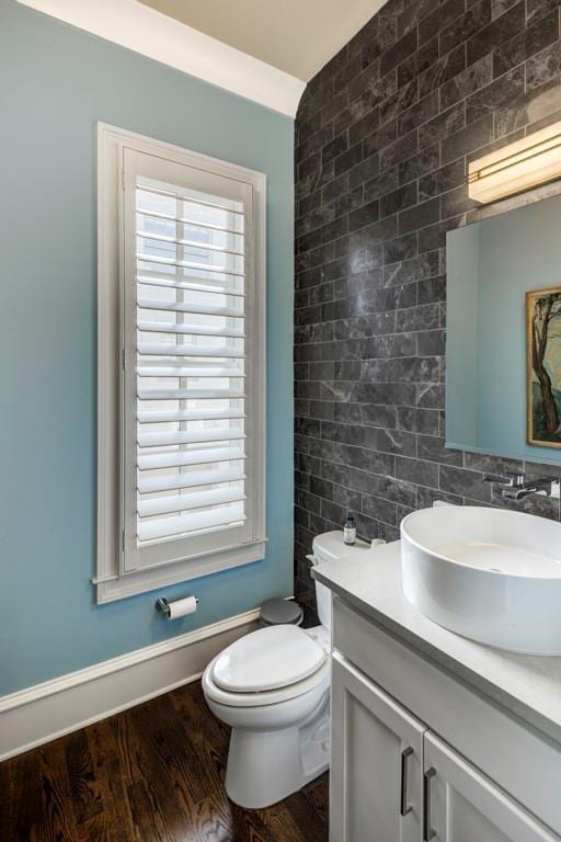 bathroom with wood finished floors, vanity, toilet, and tile walls