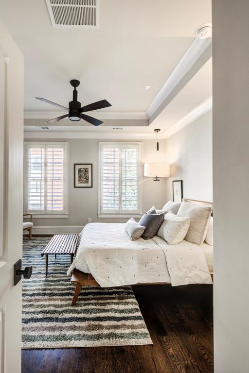 bedroom with wood finished floors, crown molding, ceiling fan, and a raised ceiling