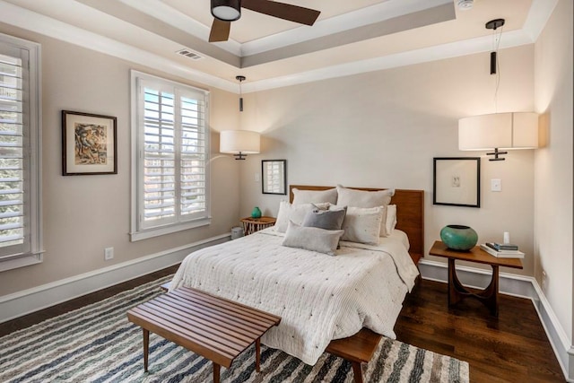 bedroom featuring wood finished floors, a raised ceiling, baseboards, and ceiling fan