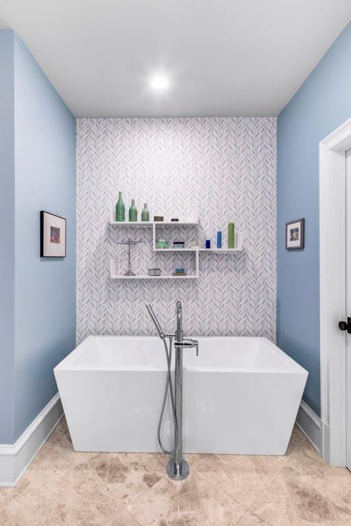 full bath featuring an accent wall, baseboards, and a soaking tub