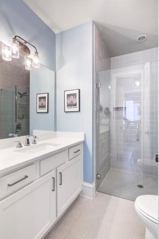 bathroom featuring a stall shower, toilet, vanity, tile patterned flooring, and baseboards