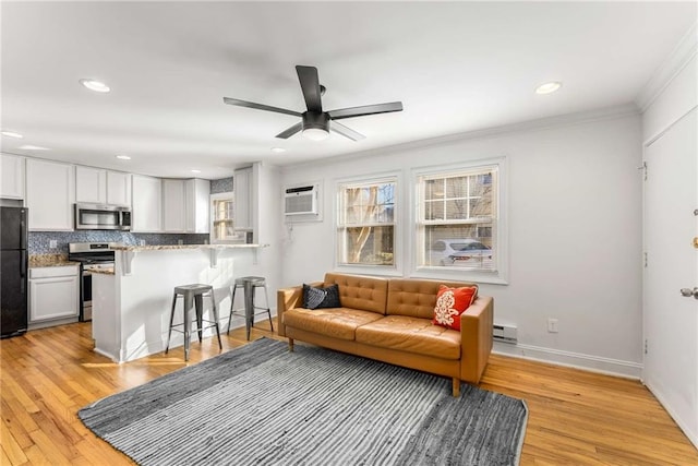 living room with light wood-type flooring, a wall mounted AC, ornamental molding, and ceiling fan