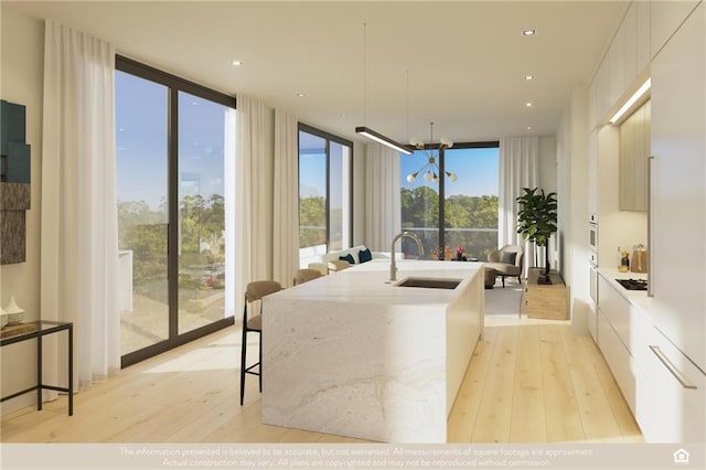 interior space featuring expansive windows, sink, a chandelier, and light hardwood / wood-style flooring