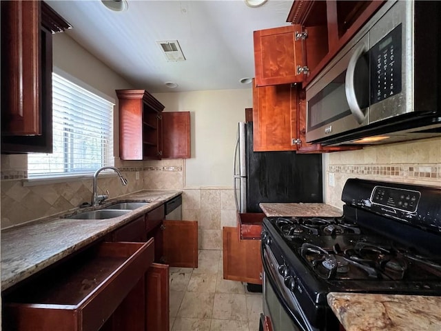 kitchen featuring sink, light stone countertops, and black gas range