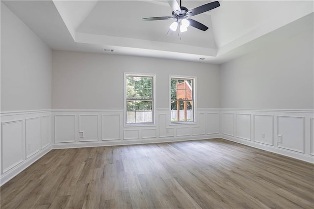 5096 Limerick Ln, Flowery Branch, GA 30542 - unfurnished room featuring a raised ceiling, ceiling fan, wood finished floors, wainscoting, and a decorative wall