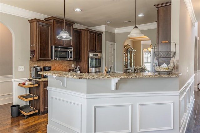 2183 Trinity Grove Ct, Dacula, GA 30019 - kitchen with arched walkways, stainless steel appliances, dark brown cabinets, light stone countertops, and a breakfast bar area