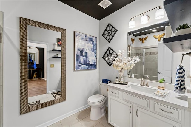 full bathroom with tile patterned flooring, a tile shower, toilet, vanity, and baseboards