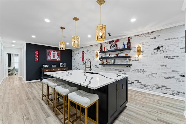 kitchen featuring a sink, baseboards, crown molding, recessed lighting, and an island with sink