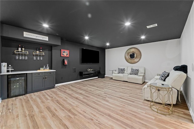 living room with beverage cooler, bar area, light wood finished floors, baseboards, and recessed lighting