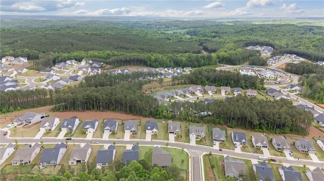 aerial view of property and surrounding area featuring a heavily wooded area and nearby suburban area