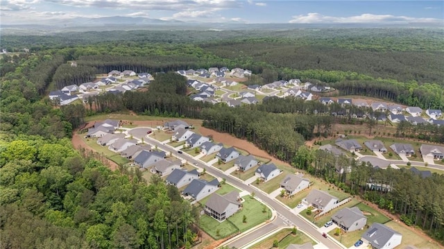 aerial view of property and surrounding area with a heavily wooded area and nearby suburban area