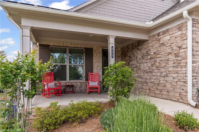 view of exterior entry featuring covered porch and stone siding