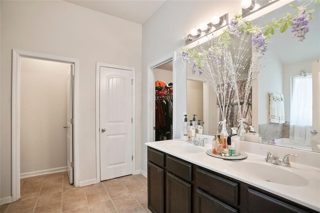 full bath featuring double vanity, baseboards, a sink, and a bath