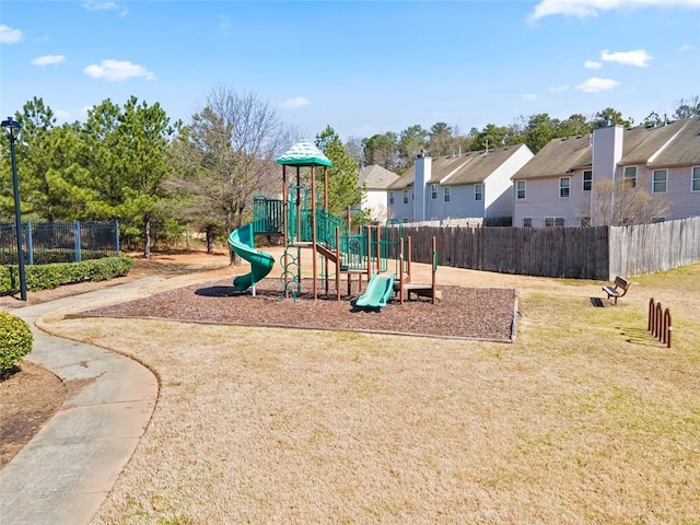 communal playground with a lawn, fence, and a residential view