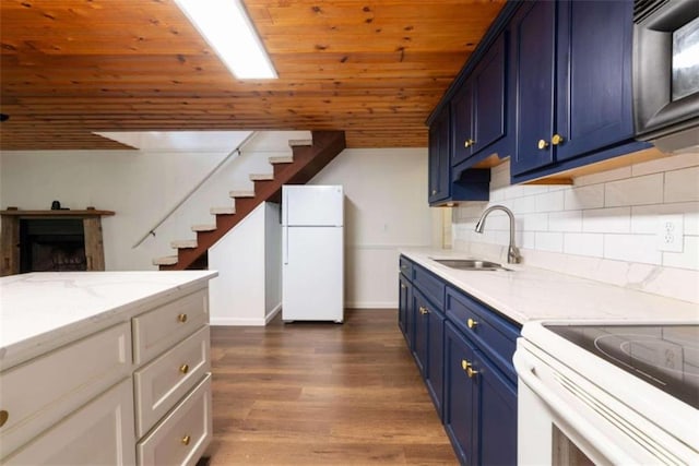 kitchen featuring light stone countertops, white appliances, blue cabinets, and dark wood-type flooring