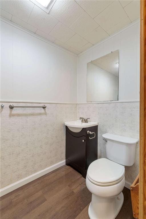 bathroom featuring hardwood / wood-style floors, vanity, tile walls, and toilet