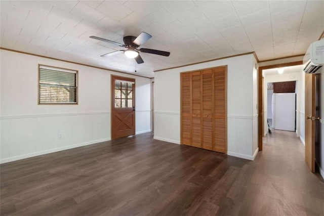 empty room featuring crown molding, a wall mounted AC, dark wood-type flooring, and ceiling fan