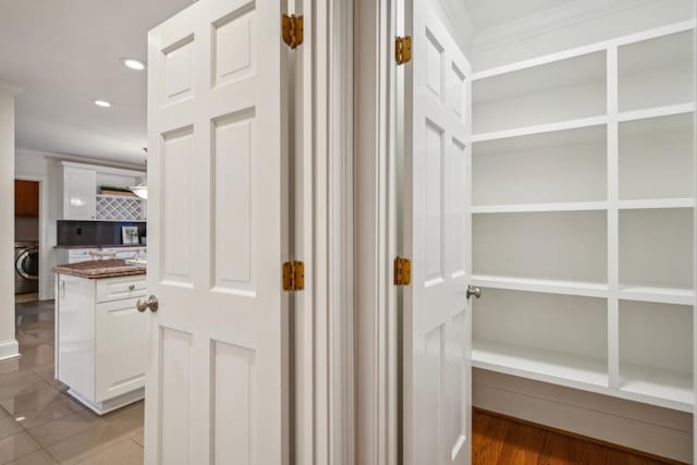 hall with tile patterned floors, washer / dryer, and crown molding