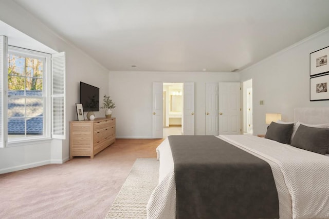 carpeted bedroom with ensuite bath and crown molding