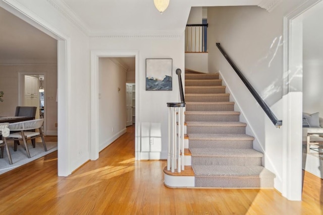 stairs featuring wood-type flooring and ornamental molding