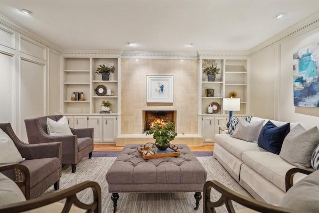 living room featuring built in shelves, light hardwood / wood-style flooring, and a tiled fireplace