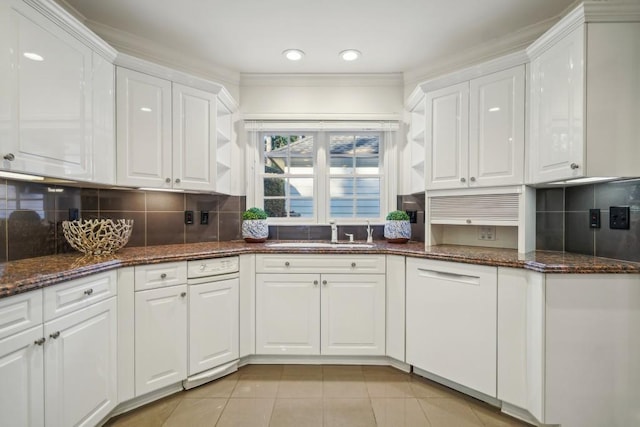 kitchen featuring tasteful backsplash, dark stone counters, sink, light tile patterned floors, and white cabinetry