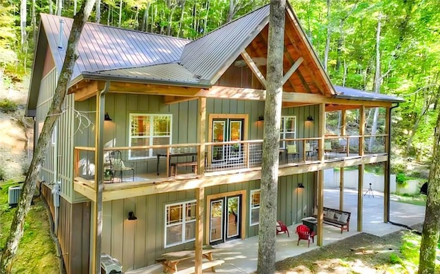 rear view of property with central air condition unit, a patio area, and a balcony