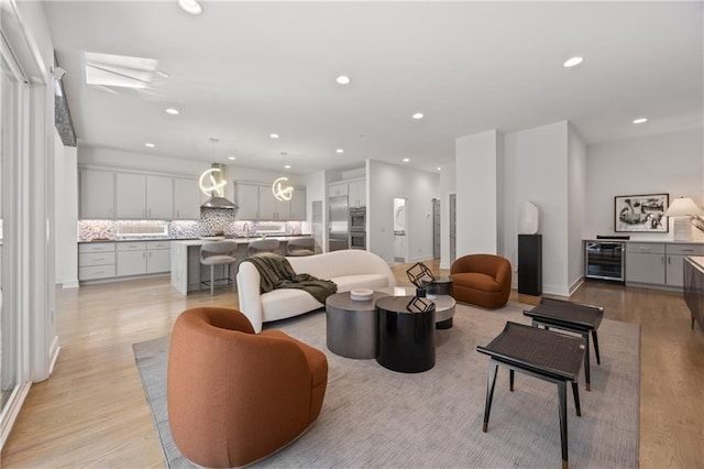 living room with sink, light hardwood / wood-style flooring, and wine cooler