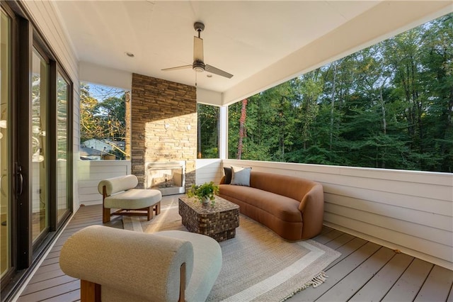 sunroom featuring ceiling fan and an outdoor stone fireplace