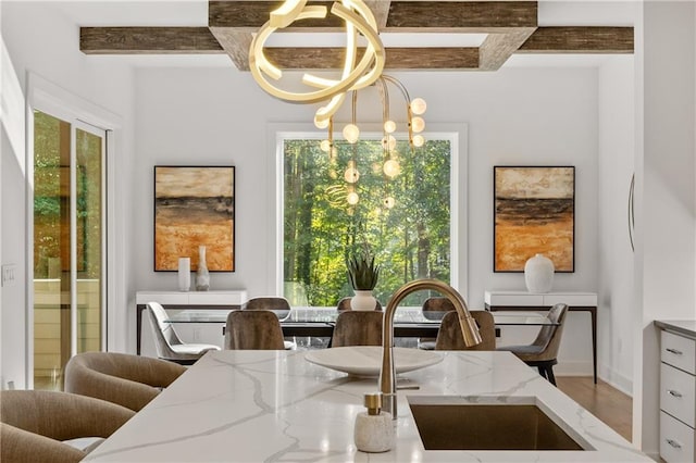 dining space with sink, hardwood / wood-style flooring, beamed ceiling, and an inviting chandelier