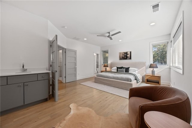 bedroom with ceiling fan, sink, and light wood-type flooring