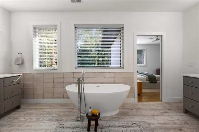 bathroom with vanity, tile walls, a tub to relax in, and hardwood / wood-style floors