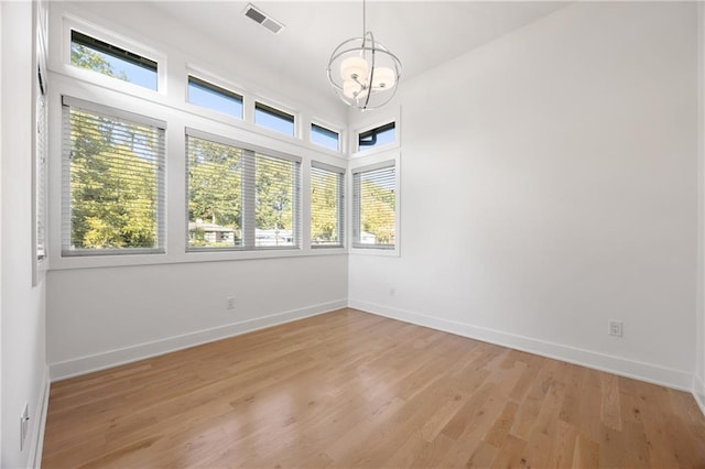 spare room with light hardwood / wood-style flooring and an inviting chandelier