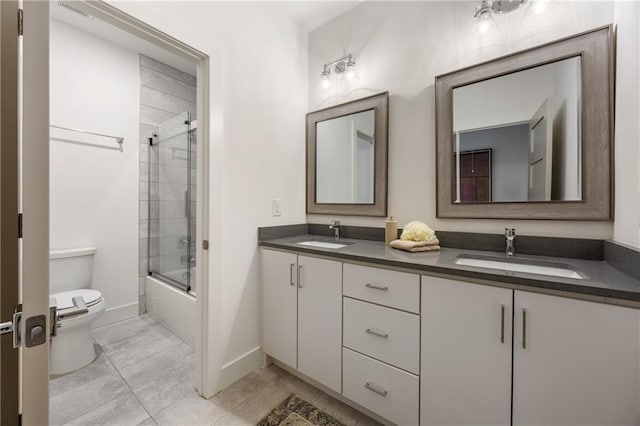 full bathroom with tile patterned floors, combined bath / shower with glass door, vanity, and toilet