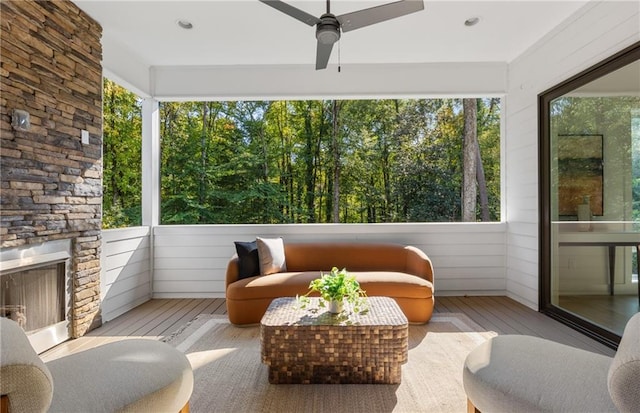 sunroom / solarium featuring ceiling fan and an outdoor stone fireplace