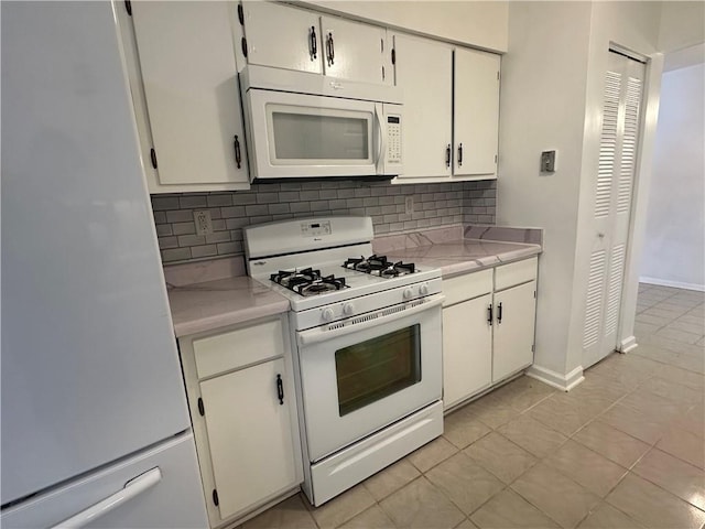 kitchen with white cabinets, light tile patterned floors, white appliances, and decorative backsplash