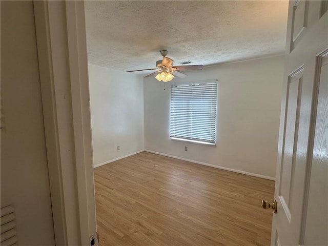 spare room with ceiling fan, a textured ceiling, and light hardwood / wood-style flooring