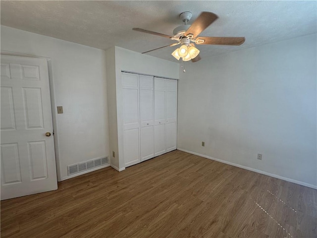 unfurnished bedroom with a closet, ceiling fan, hardwood / wood-style flooring, and a textured ceiling